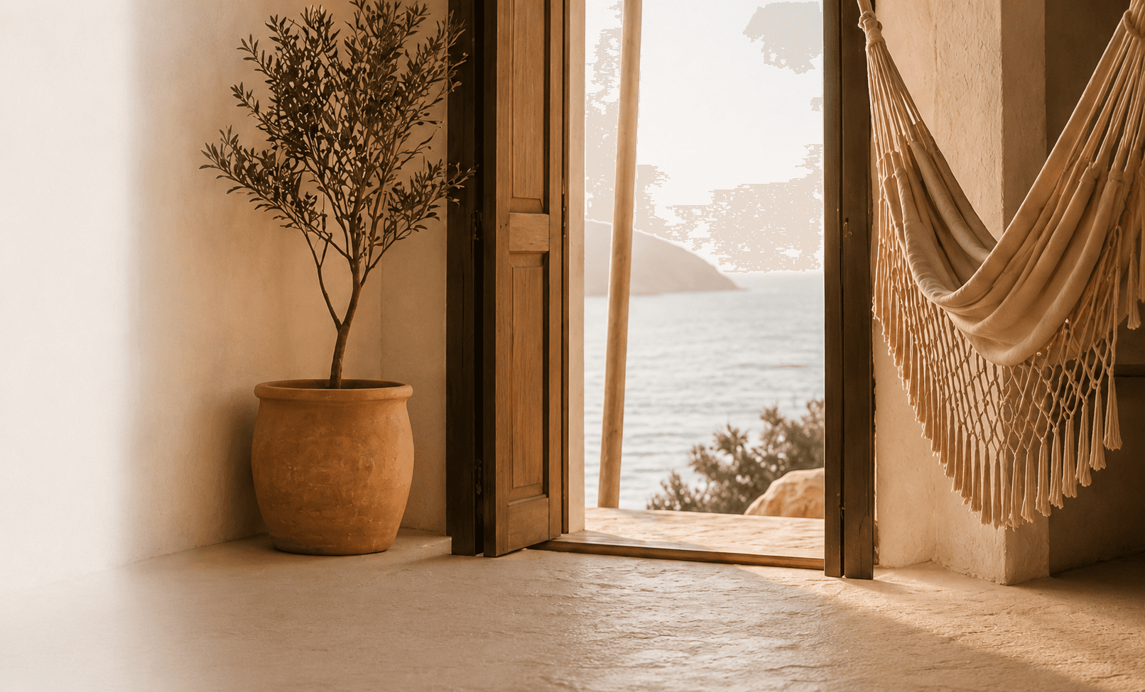 An open Mediterranean doorway with an olive tree and a hammock framing an ocean view